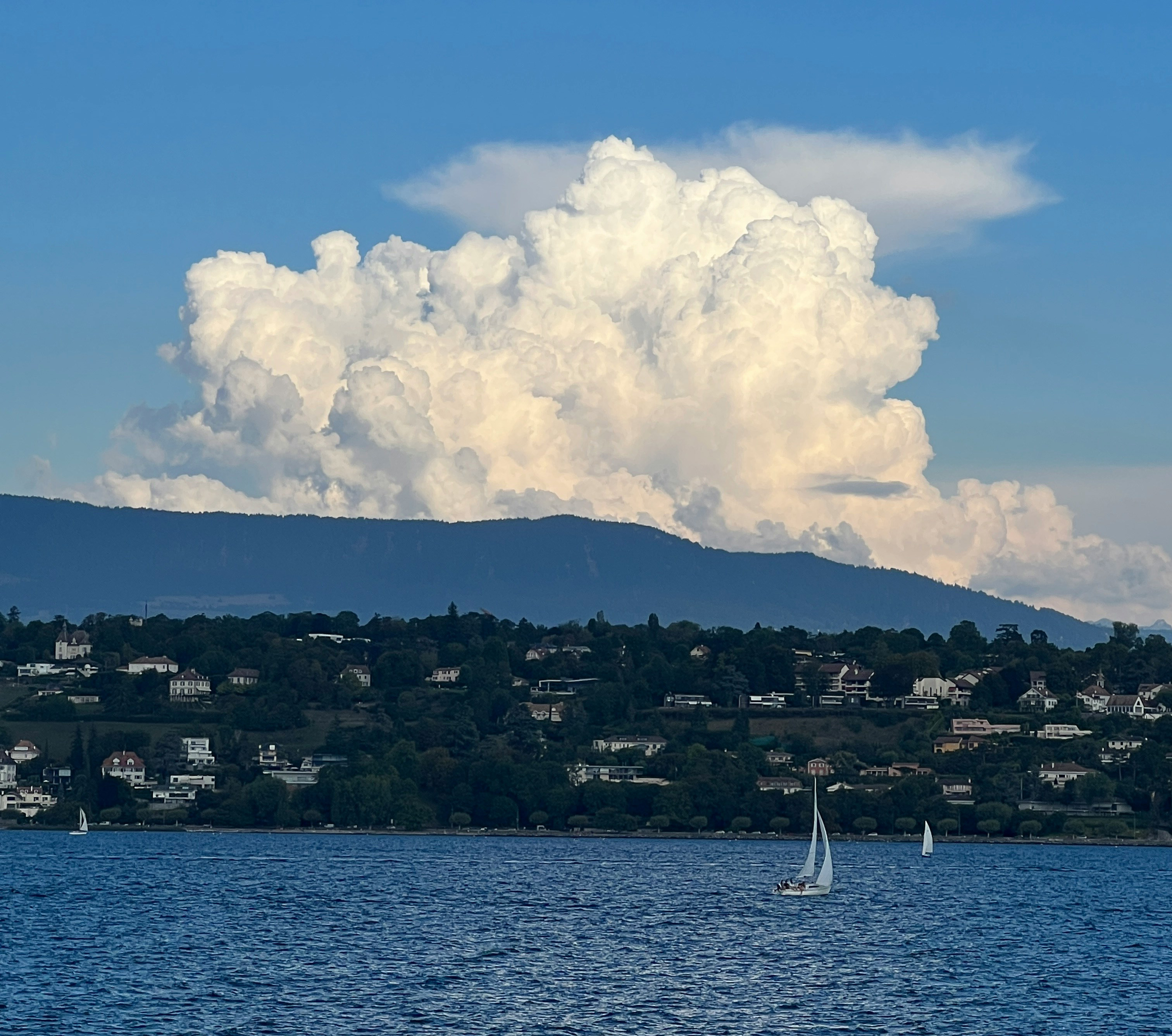Sailboat on Lac Léman beneath towering clouds